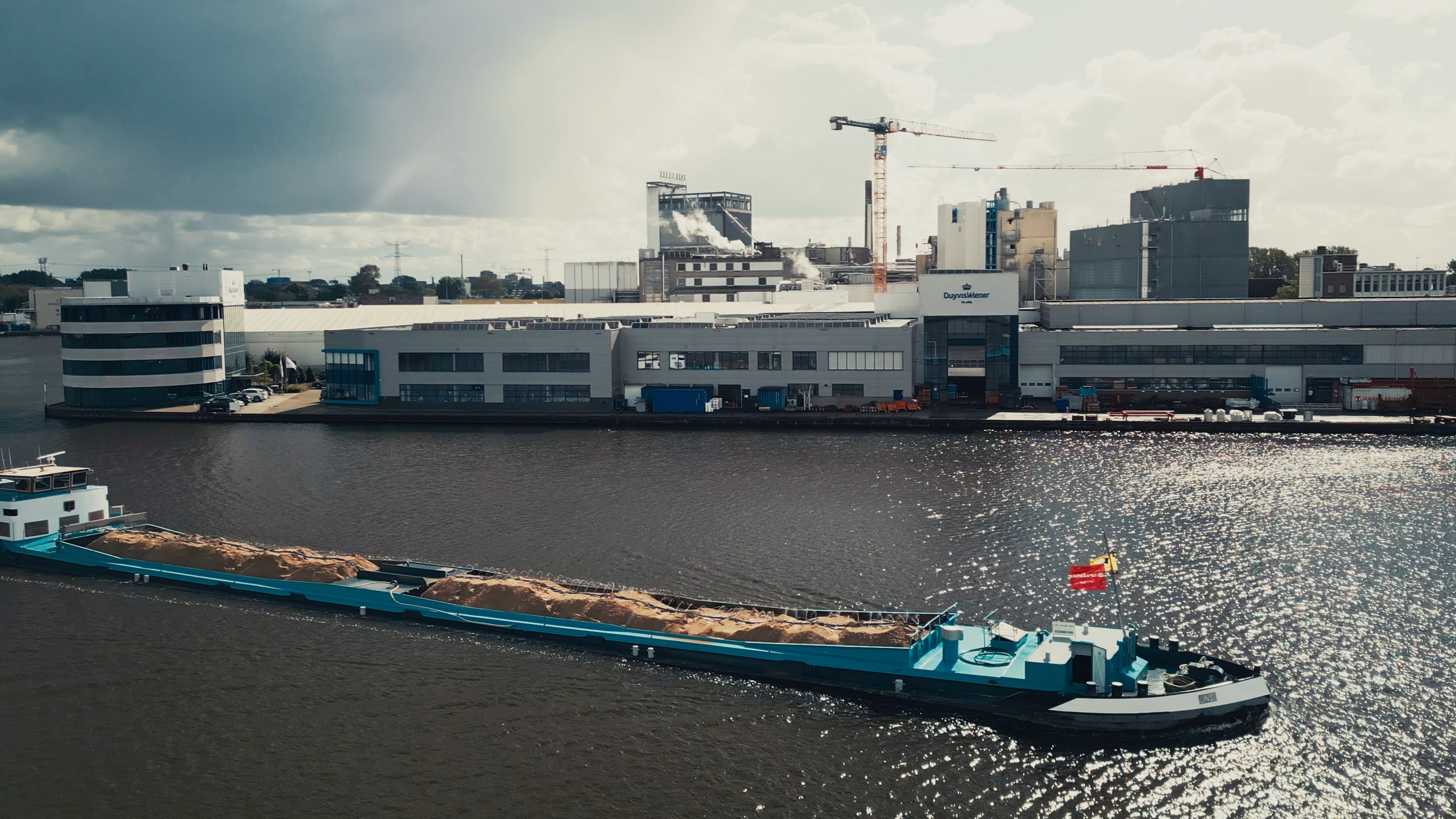 A boat passes by an industrial plant on a river