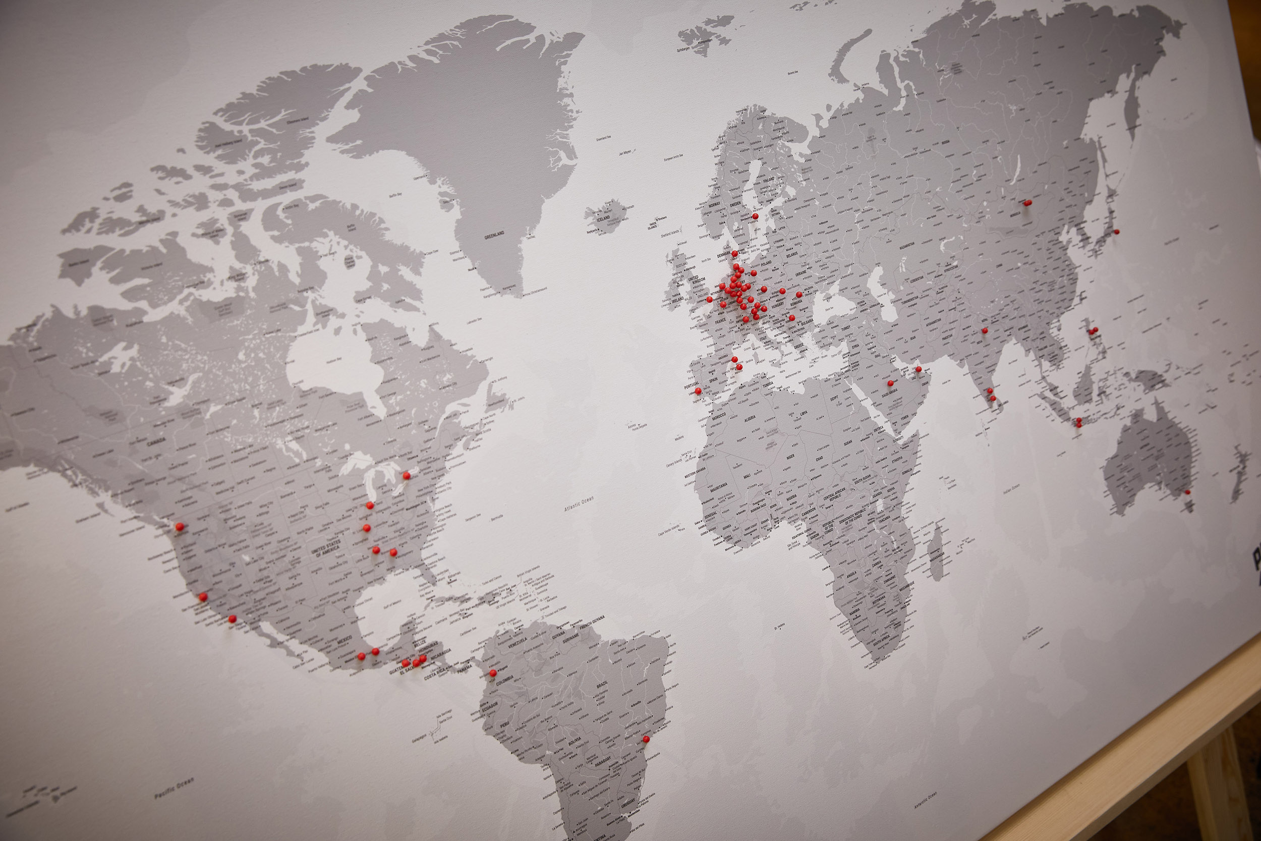 A world map stretched across a board with red pins attached to it