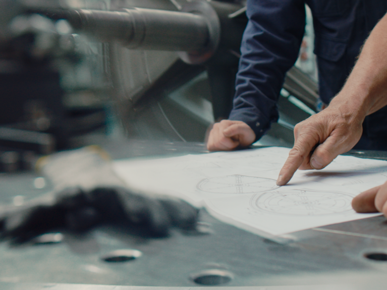 Hands pointing on paper plan in factory