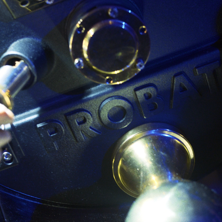 The picture shows a close-up of a Probat shop roaster focusing on the Probat logo.