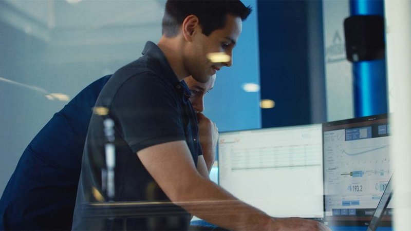 Two man are shown in front of a screen showing the Probat roasting software