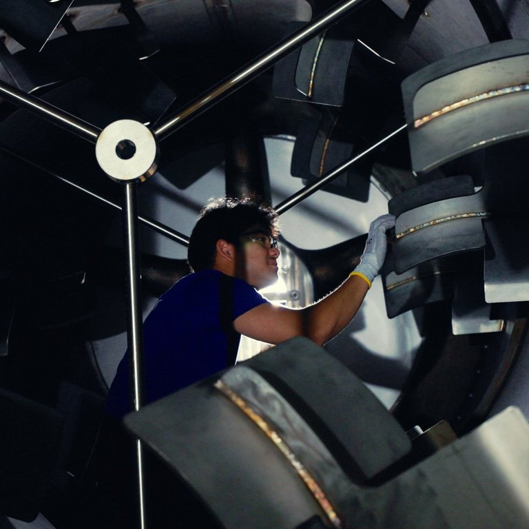 A service employee stands in the drum of a machine and performs maintenance work
