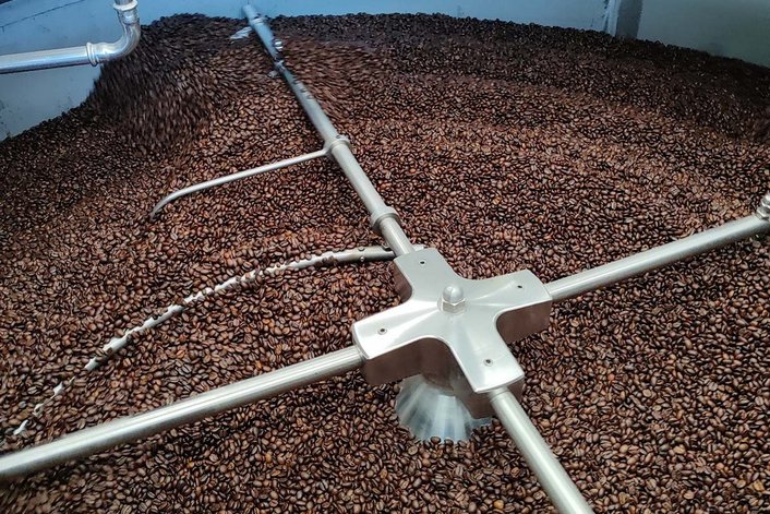 Picture of a cooling sieve with roasting beans is shown.